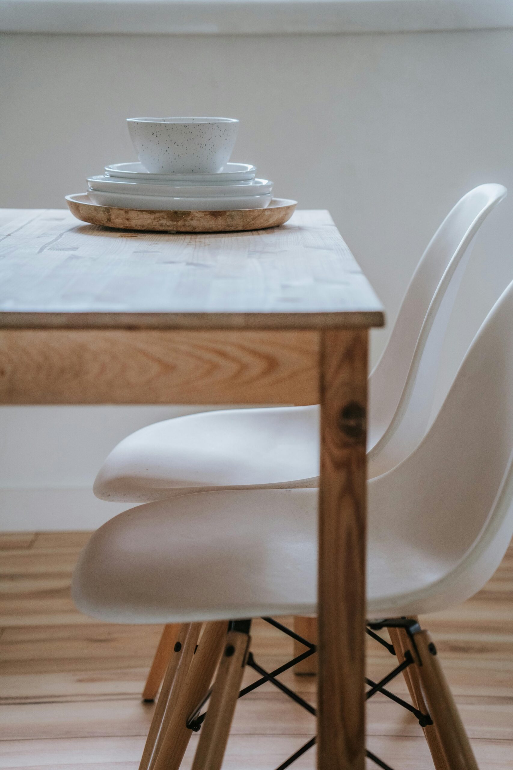Elegant minimalist dining table featuring ceramic plates and white chairs in Scandinavian style.